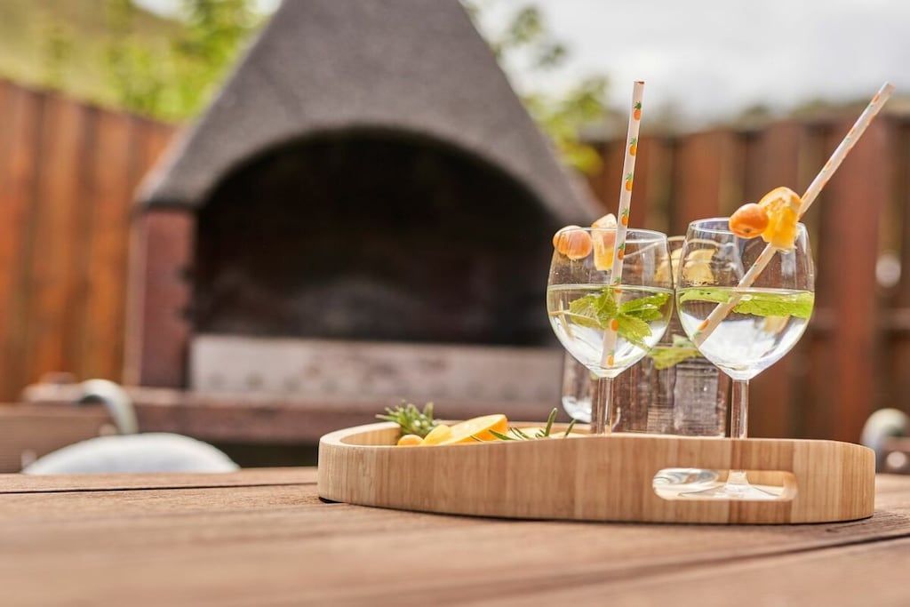 Une table en bois sur laquelle se trouve un plateau contenant trois verres d’une boisson claire, décorée de feuilles de menthe et d’une tranche d’orange.