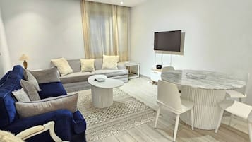 A modern living room with a sofa, armchairs, a coffee table, and a dining table.