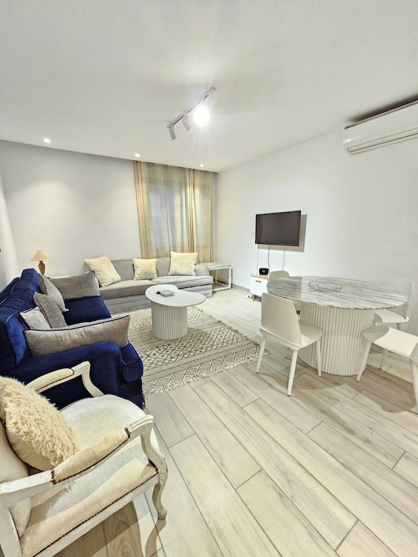 Una sala de estar moderna con un sofá, sillones, una mesa de centro y una mesa de comedor.