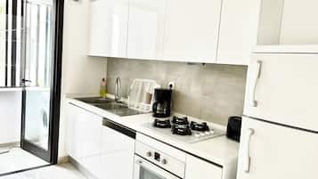 A modern kitchen with white cabinets, a stainless steel sink, a coffee maker, a toaster, and a built-in oven.