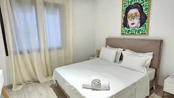 Una cama bien tendida con sábanas blancas, un cabecero y una obra de arte colgada en la pared.
