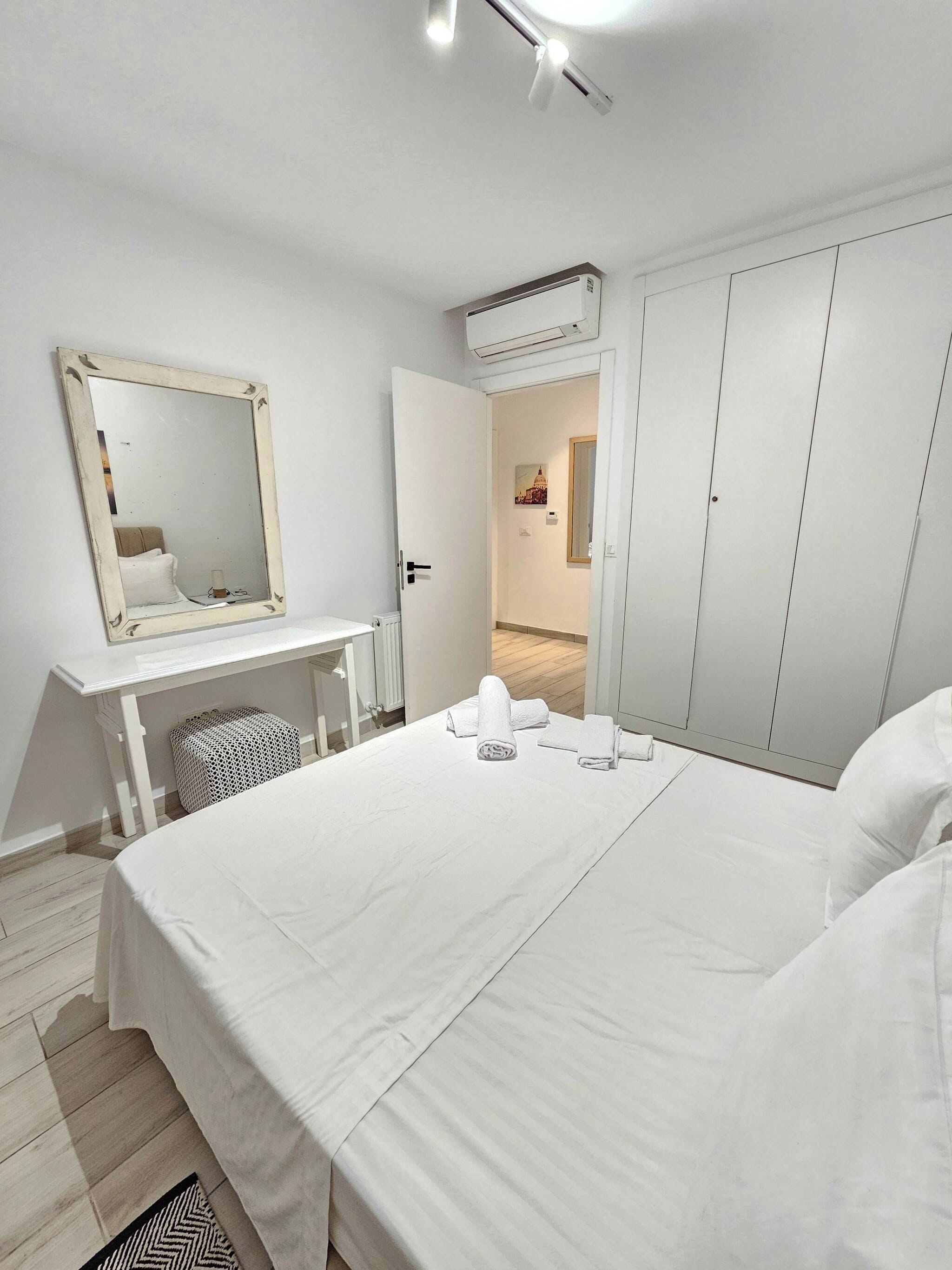 Un dormitorio con cama, cómoda, espejo y armario.