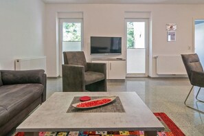Een moderne woonkamer met een bank, fauteuil en salontafel met decoratief object.