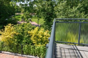 Eine Dachterrasse mit Blick auf einen Garten und ein Gebäude im Hintergrund.