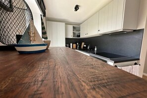 A kitchen with white cabinets, a black countertop, and a wooden floor. - Holiday apartment with 1 bedroom (Wangerooge)