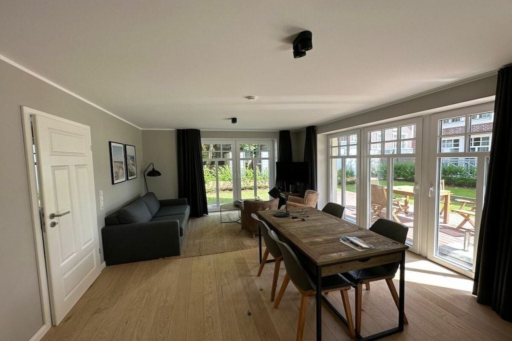 A modern living room with a sofa, a dining table, and a large window.
