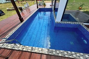 A rectangular swimming pool with a tiled edge, surrounded by a wooden deck.