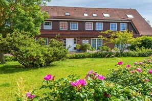 A two-story house with a red-tiled roof, a white door, and a small porch. - Apartment 107 - Beautiful Juist Woman (Juist)