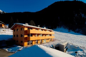 Een houten chalet met meerdere balkons, gelegen in een besneewd berggebied.