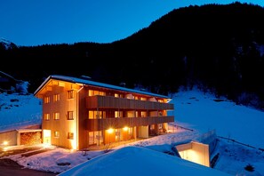 A multi-story wooden building with balconies, situated in a snowy mountainous area. - Chalet with fireplace and garden (Gaschurn)