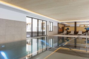 A modern hotel lobby with a glass pool, seating area, and a view of the city. - Apartment in Mittersill with swimming pool (Mittersill)