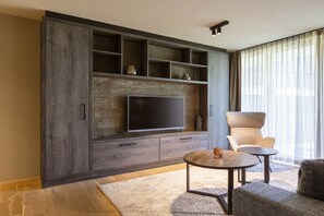 A modern living room with a large entertainment unit, a flat-screen TV, and a comfortable seating area with a round coffee table. - Apartment in Schruns with swimming pool (Schruns)