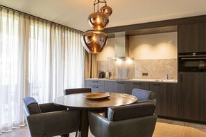 A modern kitchen with a round dining table, dark cabinetry, and a pendant light fixture. - Apartment in Schruns with swimming pool (Schruns)