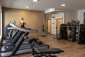 Ein Fitnessstudio mit Laufbändern, Kraftgeräten und einer Person beim Joggen.