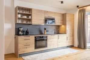 A modern kitchen with wooden cabinets, a built-in oven, and a coffee maker. - Apartment in Rauris with swimming pool (Rauris)