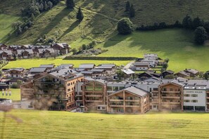 A cluster of modern buildings with multiple floors, surrounded by green fields and hills. - Apartment in Rauris with swimming pool (Rauris)