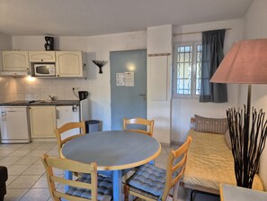 Cozinha compacta com micro-ondas, cafeteira e área de refeições com mesa e cadeiras.