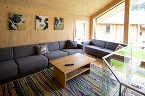 A modern living room with a sofa set, a coffee table, and artwork on the walls. - Cabin with 1 bedroom (St. Georgen am Kreischberg)