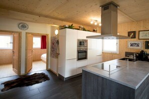 Eine moderne Küche mit weißen Schränken, einer zentralen Kochinsel und einem eingebauten Backofen.
