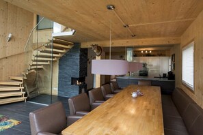 Ein modernes Interieur mit einem Holztisch, Ledersesseln, einer Treppe und einer Küchenzeile.