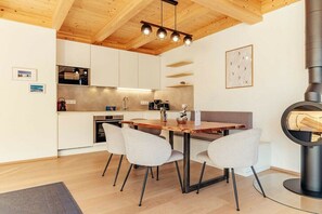 A modern kitchen with white cabinets, a wooden dining table, and a built-in stove. - Cabin in Niederwölz with sauna (Niederwölz)