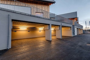 Un bâtiment moderne doté d’un parking couvert et d’un balcon en bois.