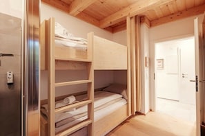A bunk bed room with a wooden ceiling and a door leading to another room. - Chalet #2 with 3 bedrooms and sauna (Niederwölz)