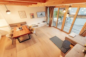 A modern interior with a wooden dining table, a sofa, and a TV on the wall. - Chalet #2 with 3 bedrooms and sauna (Niederwölz)