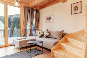 A cozy room with a sofa, a small table, and a staircase. - Chalet #2 with 3 bedrooms and sauna (Niederwölz)