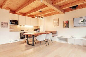 A modern kitchen with wooden beams, white cabinetry, and a dining area with a wooden table and chairs. - Chalet #2 with 3 bedrooms and sauna (Niederwölz)