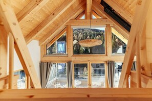 Ein Holzinnenraum mit hoher Decke, großen Fenstern und einer hängenden Leuchte.
