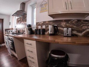Eine Küche mit Holzausziehtisch, Herd, Spüle und Schränken.
