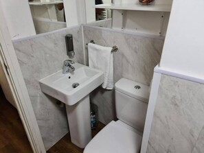 Ein Badezimmer mit einem weißen Waschbecken, einer Toilette und einem Handtuch an der Wand.
