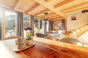 A wooden interior with a dining table, chairs, a sofa, and a staircase. - Chalet #7 with 3 bedrooms and sauna (Niederwölz)
