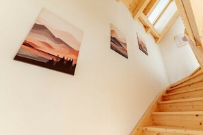 A wooden staircase leading to a loft with a skylight, and three landscape paintings on the wall. - Chalet #7 with 3 bedrooms and sauna (Niederwölz)