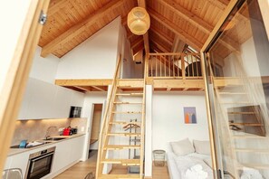 Ein Loft-Zimmer mit einer Holztreppe, einer Küchenzeile und einem Bett.