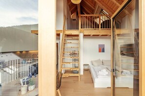 Ein modernes Interieur mit einer Holztreppe, einem weißen Sofa und einer Glastrennwand.