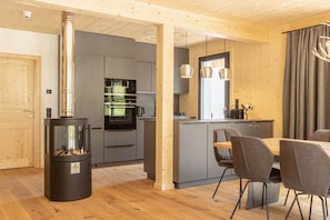 A modern kitchen with grey cabinets, a black stove, and a dining area with grey chairs.