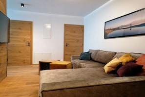 A modern living room with a sofa, ottoman, and a painting on the wall. - Holiday apartment with 2 bedrooms (Rauris)