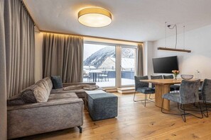 Ein modernes Wohnzimmer mit einer Couch, Hocker und einem Essbereich mit Stühlen.