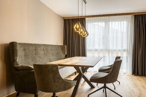 Ein moderner Essbereich mit Holztisch, vier Stühlen und einer Pendelleuchte.