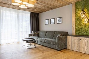 A modern living room with a grey sofa, a round coffee table, and a wooden ceiling. - Apartment in Fügen with swimming pool (Fügen)