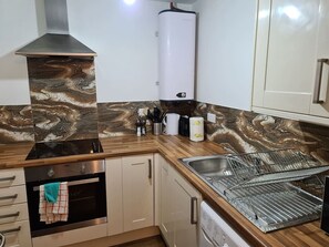 Eine Küche mit Backofen, Spüle aus Edelstahl und Durchlauferhitzer.