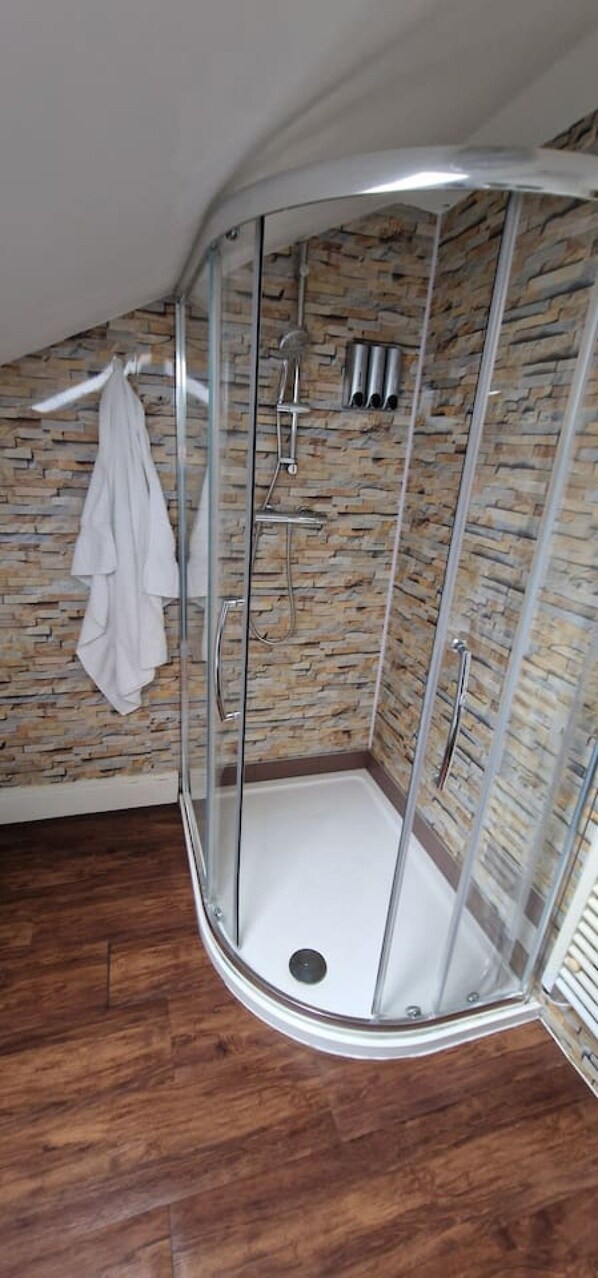 Eine gläserne Dusche mit einer Wand aus Stein im Hintergrund.