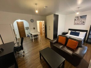 Ein kompakter Wohnraum mit Bett, Sofa, Schreibtisch und Essbereich.