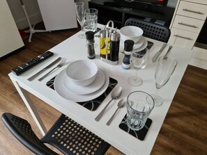 Ein Esstisch mit Geschirr, Besteck, Gläsern und Gewürzen.