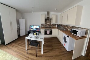 Eine kleine Küche mit Esstisch, Mikrowelle, Waschmaschine und Fernseher.