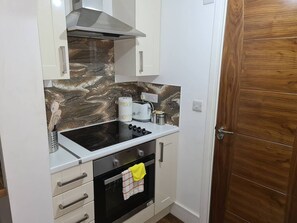 Eine kleine Küche mit Herd, Backofen und weißen Schränken.