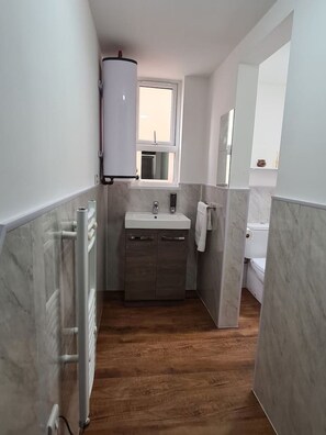 Ein Badezimmer mit einem weißen Waschbecken, einem Spiegel, einem Handtuchhalter und einer Toilette.