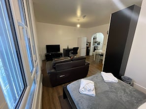 Een moderne woonkamer met een bank, een flatscreen televisie en een eethoek met een tafel en stoelen.